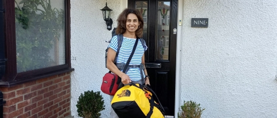 Anissa Msallem standing with a large bag outside front door ready to set off for the Mahale Mountains Challenge.