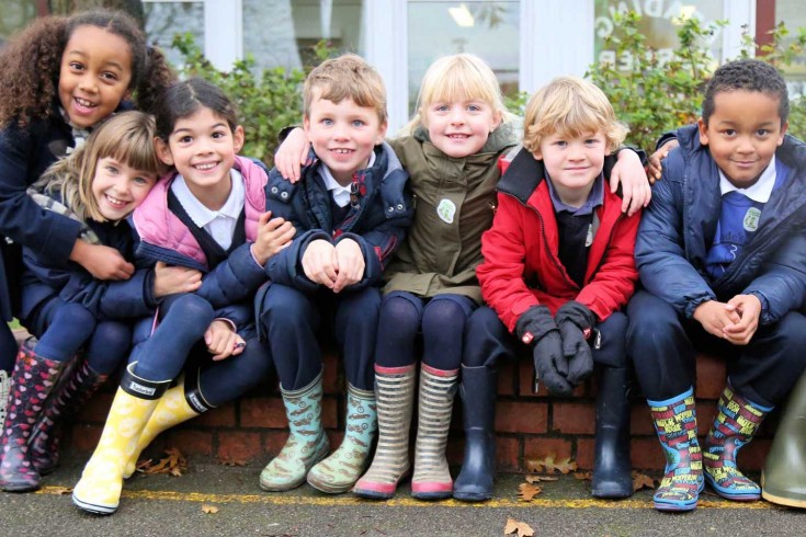Children in wellies sitting on a low wall