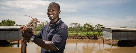 A fish farmer showing off a newly caught catfish