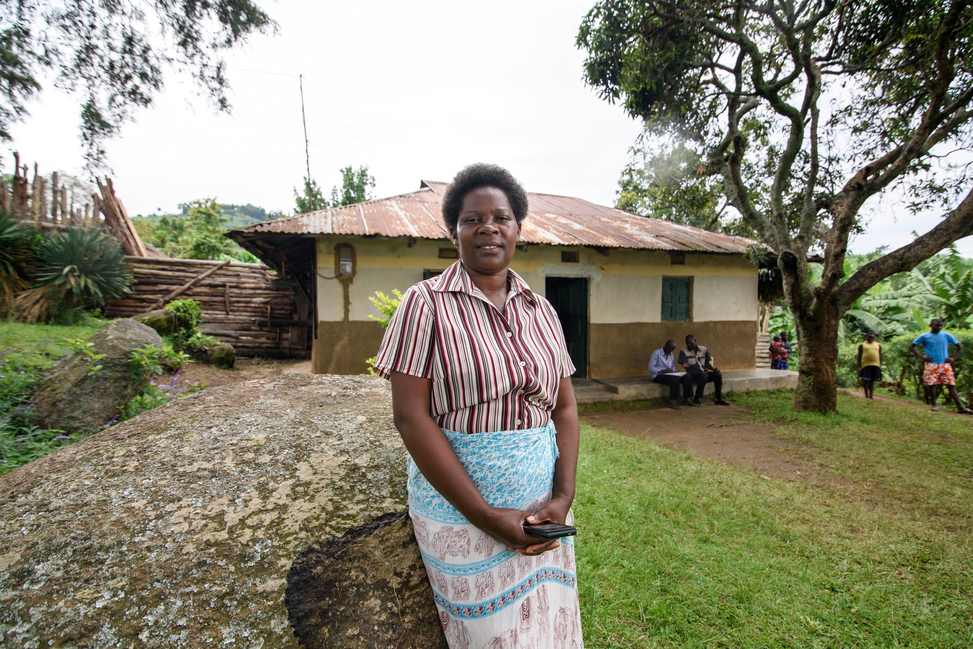 Patience, a coffee farmer from Kanungu, standing outside of her home.