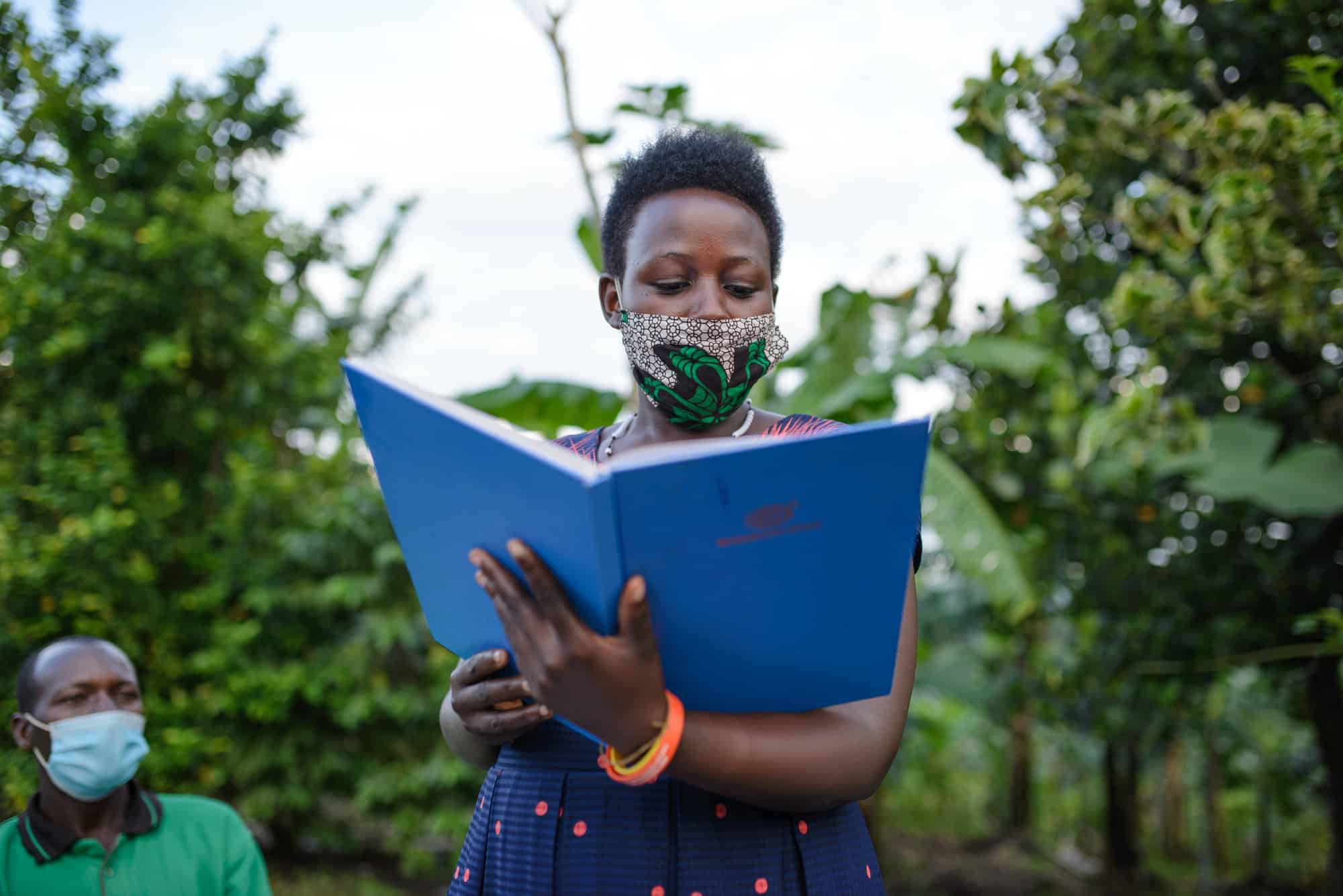 Hildah reading from a book in her role as treasurer of the Banyakinkizi Coffee Producers and Processors Cooperative.