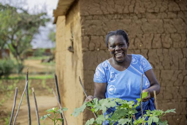 Female farmer Damaris standing her with her crops.