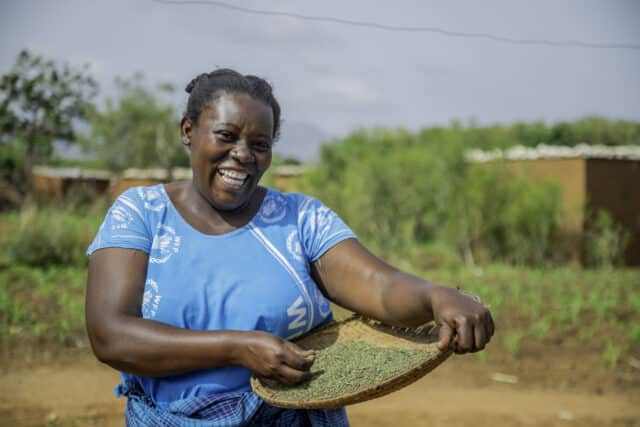 Female farmer Damaris holding her harvested sorghum.