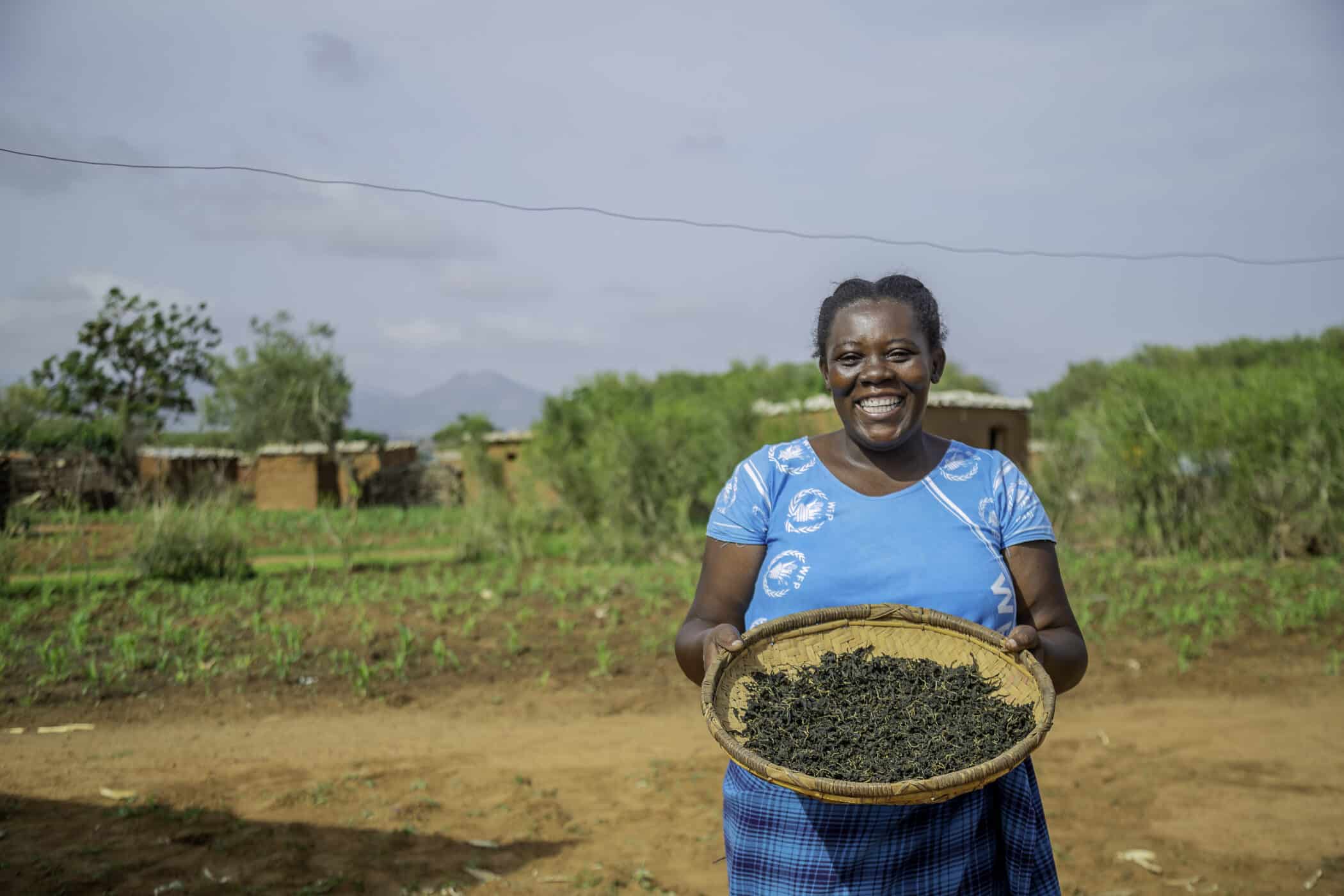 Female farmer Damaris holding her harvested sorghum.