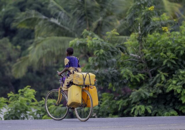 A girl rides a bicycle along a road in Tanzania.