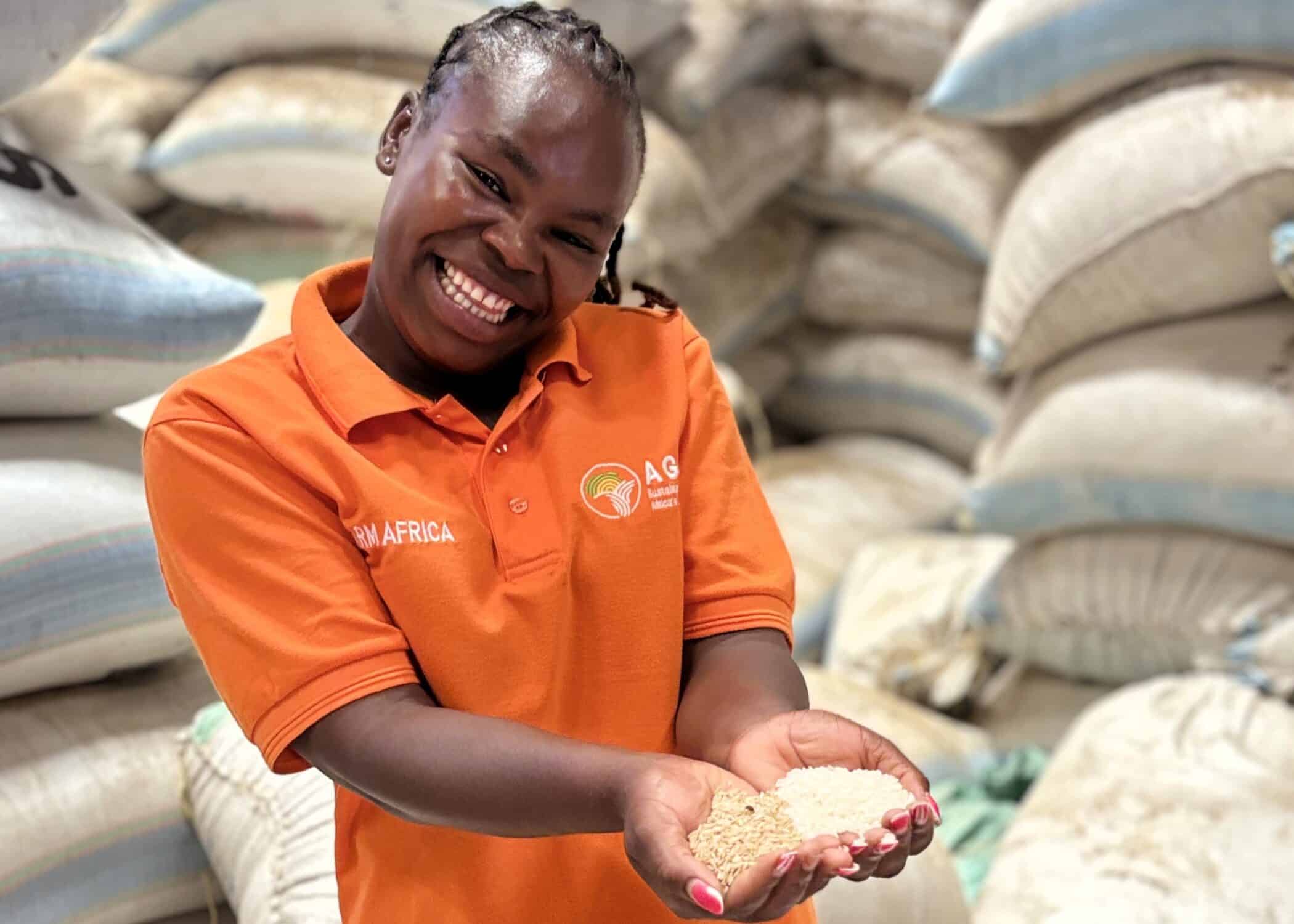 Kenyan farmer Felista holding handfuls of paddy rice and milled rice.