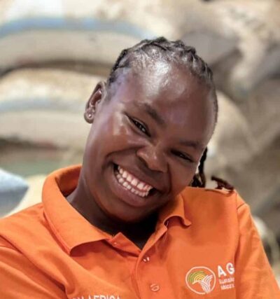 Farm Africa employee in Kenya, Felista, holding a handful of grains in a warehouse.