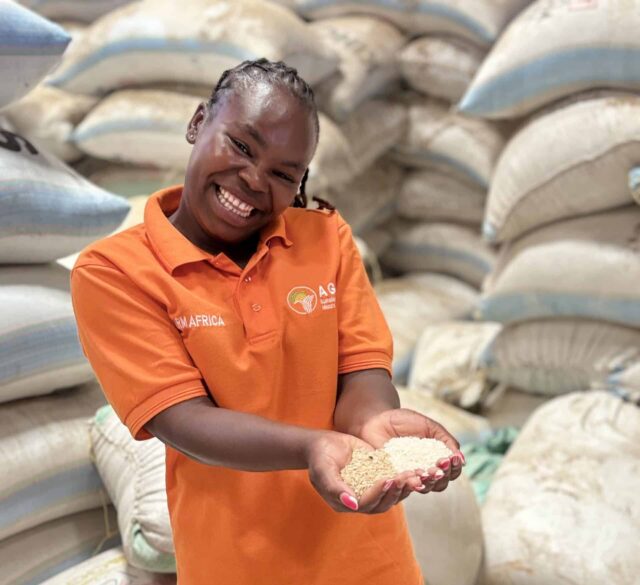 Felista, a Village-based Advisor in Kenya holding a handful of grains in a warehouse. Credit: Farm Africa / Camilla Turner.
