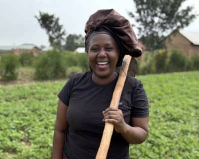 Judith a smallholder farmer from Uganda holding a hoe.