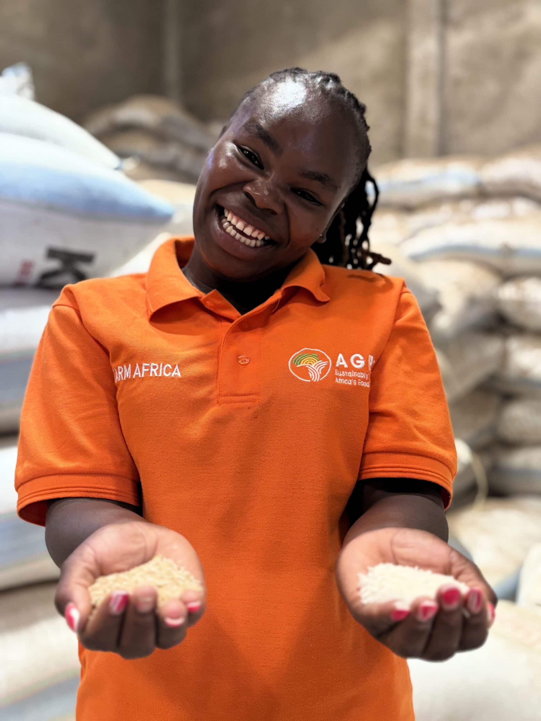 Farm Africa employee in Kenya, Felista, holding a handful of grains in a warehouse.