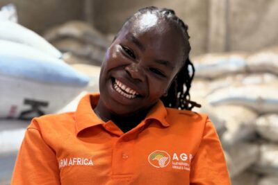Farm Africa employee in Kenya, Felista, holding a handful of grains in a warehouse.