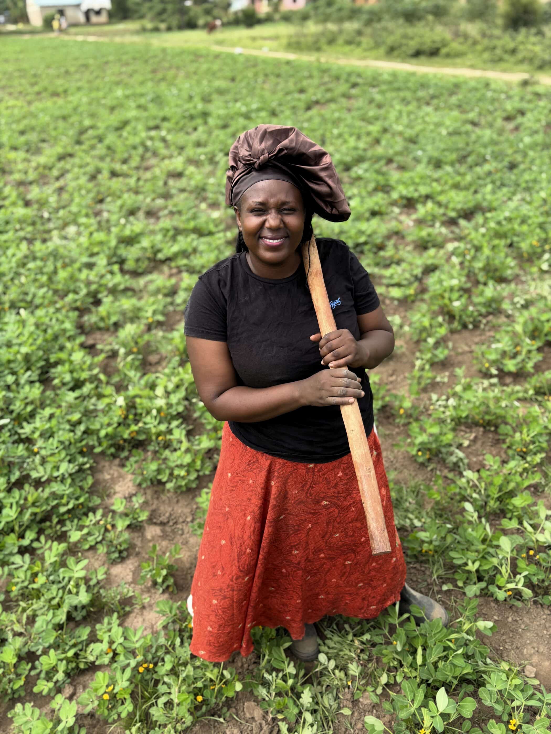 Judith a smallholder farmer from Uganda holding a hoe.