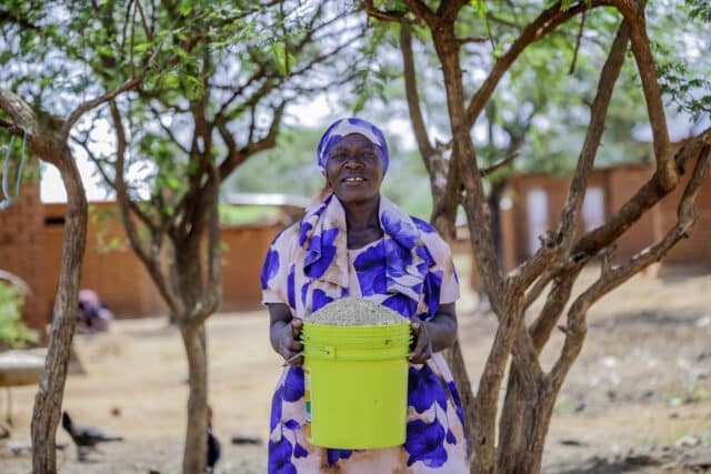 Suzana holding a bucket full of freshly harvested grains.