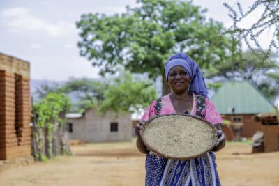 Tanzanian farmer Judith holding holding her harvested sorghum.