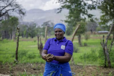 Tanzanian farmer Teluvina holding a handful of soil on her farm.