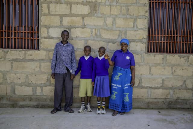 Tanzanian farmer Teluvina stood outside her new home with her husband and children.