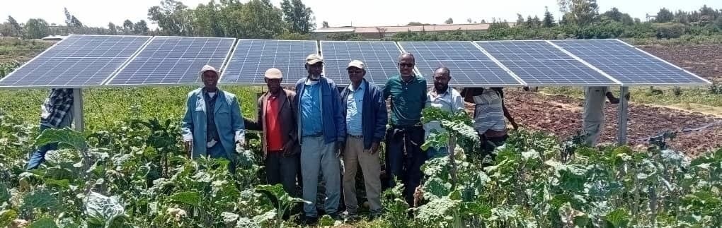 Farmers grouped standing in front of solar panels.